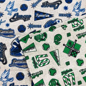 Op de afbeelding: Lichtgrijze stof met herhaalde patronen van blauwe en groene emblemen, tekst en sportuitrusting. De ontwerpen omvatten de woorden "Ravenclaw", "Seeker", "Chaser" en "Slytherin", samen met sterren, vogels en sportballen.