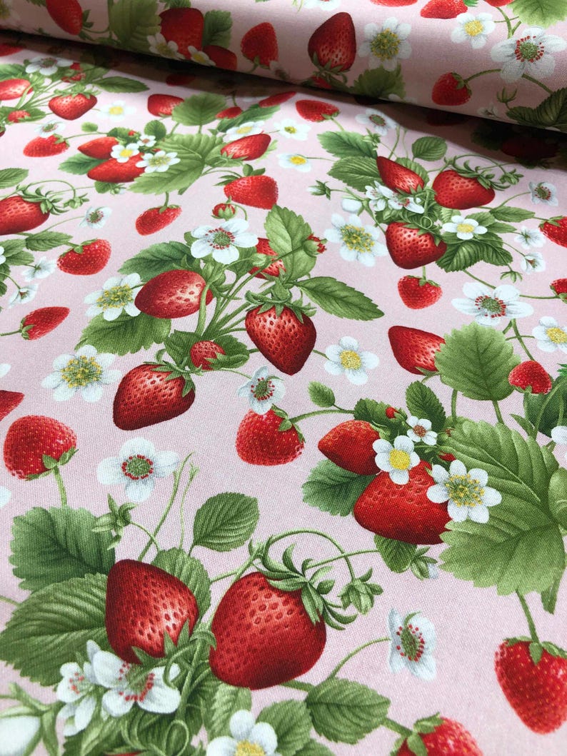 May include: Pink fabric with a repeating pattern of red strawberries and white flowers. The strawberries are depicted with green leaves and stems.