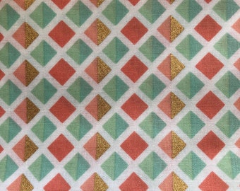 Puede incluir: Tela blanca con un patrón repetido de formas de diamante de coral y verde con acentos dorados. La tela se mide con una regla en pulgadas.