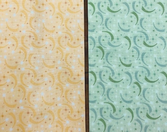 May include: Two pieces of fabric side by side. The left piece is yellow with a repeating pattern of white and orange crescent moons and stars. The right piece is light green with a repeating pattern of dark green crescent moons and stars.