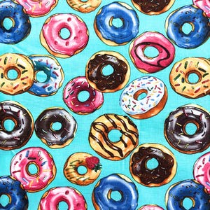 May include: A fabric pattern featuring a repeating print of various donuts on a bright turquoise background. The donuts include pink, blue, chocolate, and glazed varieties, some topped with colorful sprinkles or chocolate drizzles.