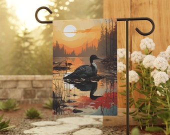 May include: A garden flag with a sunset scene featuring a loon swimming in a lake. The flag is attached to a black metal pole.