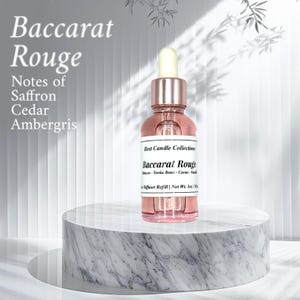 May include: A pink diffuser refill bottle with a dropper, labelled "Baccarat Rouge" with notes of saffron, cedar, and ambergris. The bottle is on a marble-patterned pedestal. The text "Best Candle Collection" is also visible.