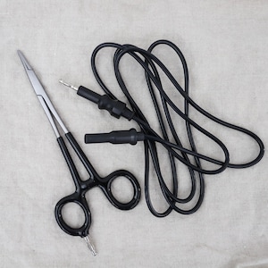 May include: A pair of silver surgical forceps with black handles and a black electrical cord with two black probes.