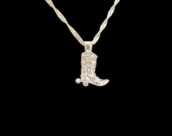 May include: A silver necklace with a boot charm. The boot has a detailed design and a spur.