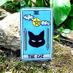 Könnte beinhalten: Ein blauer Tarotkarten-Patch mit dem Text "XVI THE CAT" und einer schwarzen Katze mit einem gelben Stern im Hintergrund.