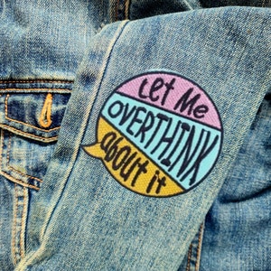 May include: A blue denim jacket with a colorful embroidered patch that says "Let me overthink about it".
