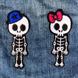 Peut inclure: Deux patchs brodés à repasser représentant des squelettes. Un squelette porte un chapeau de marin bleu avec une étoile blanche. L'autre squelette porte un nœud rose.