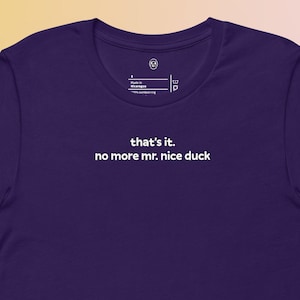 May include: A short-sleeved, deep purple t-shirt with the text "that's it. no more mr. nice duck" printed in white. The shirt has a crew neck and a relaxed fit, suitable for casual wear.