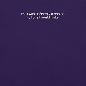 May include: A deep purple fabric background featuring the white text that reads, that was definitely a choice. not one i would make. The lettering is centered in the upper portion of the frame and uses a simple, clean, sans-serif typeface.