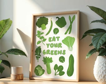 May include: A framed print with a white background and green illustrations of various vegetables. The text "Eat Your Greens" is written in green letters.