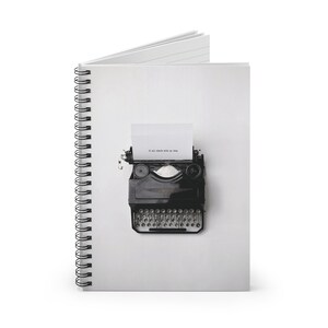 以下が含まれることがあります： タイプライターの画像が印刷された、スパイラルバインディングされたノート。タイプライターはヴィンテージで、紙には「It all starts with an idea.」というテキストが印刷されています。