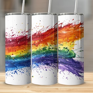 May include: Three stainless steel tumblers with a rainbow paint splatter design. The tumblers are white with a rainbow design that includes red, orange, yellow, green, blue, indigo, and violet. The design is a splatter effect with the colors blending together. The tumblers are all the same size and have a silver lid. The text "Pride Month 20" is visible on the rightmost tumbler.
