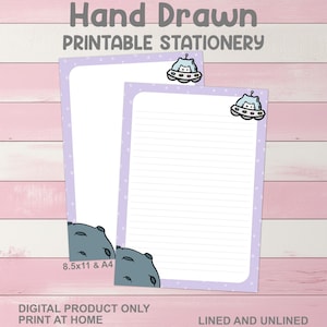 May include: Two sheets of printable stationery with a light purple border and white polka dots. The top of each sheet features a cartoon spaceship with a cat inside. The bottom corners have a gray rock design. Text at the top reads "Hand Drawn Printable Stationery".