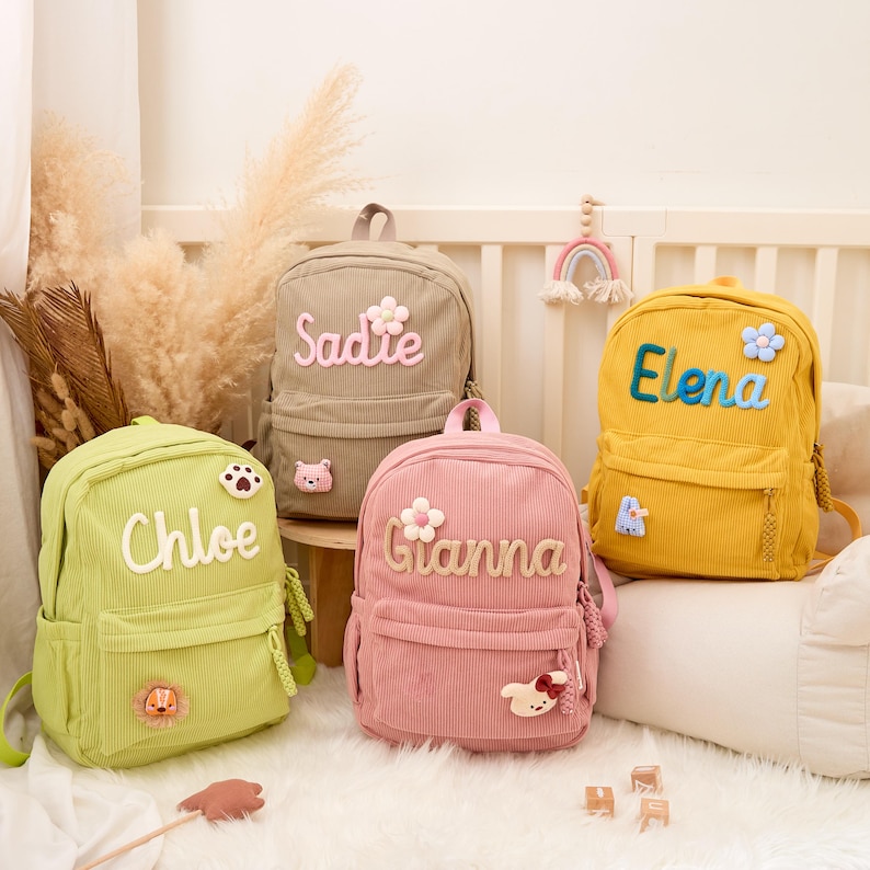 Pu&ograve; includere: Quattro zaini in velluto a coste dai colori pastello: verde, rosa, beige e giallo. Ogni zaino ha un nome ricamato: Chloe, Gianna, Sadie ed Elena. Gli zaini hanno toppe a tema floreale e animale.