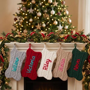 Peut inclure: Cinq chaussettes de Noël en forme d'os en tricot torsadé gris, rouge, blanc, beige et vert foncé. Chaque chaussette présente un prénom personnalisé brodé dans une couleur contrastante : Willow, Victoria, Riley, Stella et Nova.