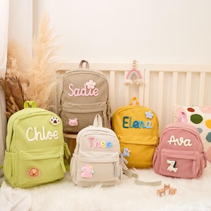 Pu&ograve; includere: Cinque zaini in velluto a coste in vari colori: verde chiaro, beige, giallo, bianco sporco e rosa. Ogni zaino presenta un nome ricamato in un colore a contrasto, insieme a toppe decorative. Gli zaini sono progettati per bambini.