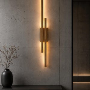 Pode incluir: Arandela de parede moderna em madeira, emitindo uma luz quente. O design incorpora ripas de madeira verticais e horizontais, oferecendo uma estética minimalista. A luminária é montada em uma parede cinza texturizada, realçando o ambiente moderno do ambiente.