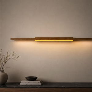 Könnte beinhalten: Eine moderne, rechteckige Wandleuchte aus Holz mit warmem, gelbem Licht. Die Leuchte besteht aus hellbraunem Holz und ist horizontal an einer neutralfarbenen Wand angebracht. Das Design ist minimalistisch und elegant, geeignet für die Inneneinrichtung.