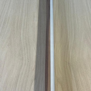 May include: A rectangular wooden trim piece with a recessed, bright white light strip. The wood has a natural grain and a warm brown color. The light strip is centered along the length of the trim.