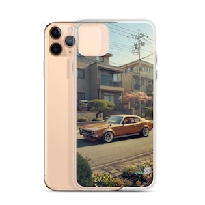 May include: A phone case featuring a vintage brown car parked on a residential street. The car is a classic coupe with a sleek design. The background shows houses and a clear sky, creating a nostalgic scene.