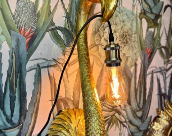 Lampada da parete antica a forma di testa di fenicottero color oro.