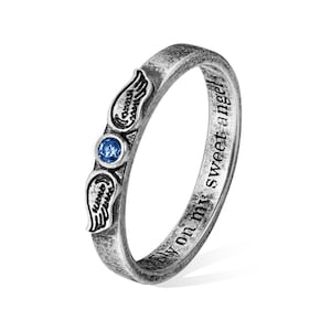 Op de afbeelding: Zilverkleurige ring met een blauwe edelsteen en vleugelaccenten. De ring heeft de inscriptie "fly on my sweet angel". Het is een sieraad.