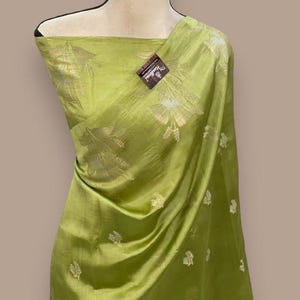 Puede incluir: Un sari de seda verde con un patr&oacute;n floral plateado. El sari est&aacute; drapeado sobre un maniqu&iacute;.