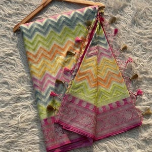 Puede incluir: Un pañuelo de seda colorido, multicolor, con estampado de zigzag, con borde rosa y borlas doradas.