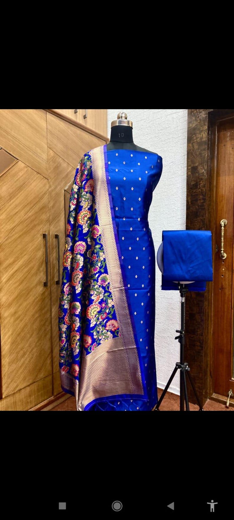 May include: A blue and gold patterned fabric with a floral design. The fabric is draped over a dress form and is accompanied by a solid blue fabric.