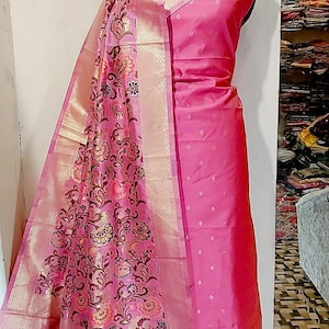 May include: A pink and gold patterned silk dupatta with a pink silk dress. The dupatta has a floral design with gold accents. The dress has a dotted pattern.
