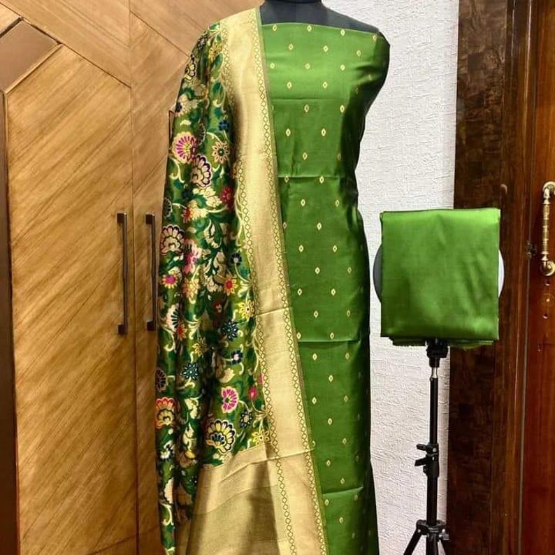 May include: A green dress fabric with a matching dupatta and a plain green fabric piece. The dupatta has a floral pattern with gold accents. The dress fabric has a small diamond pattern.