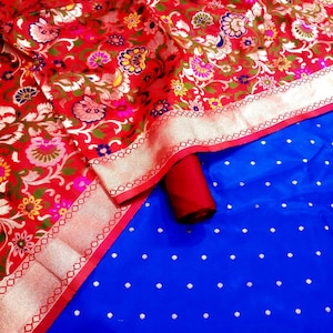 May include: A red and gold fabric with a floral pattern and a silver border. The fabric is folded over a blue fabric with white polka dots.