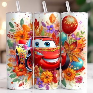 May include: A white tumbler with a red, yellow and green floral design. The tumbler features a cartoon image of a red racing car with a smiling face. The car is surrounded by flowers and leaves.