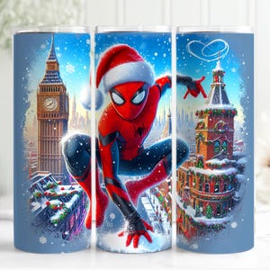 May include: A blue tumbler featuring a festive Spider-Man in a Santa hat, set against a snowy London backdrop with Big Ben and decorated buildings. The design is a vibrant illustration with a winter holiday theme.