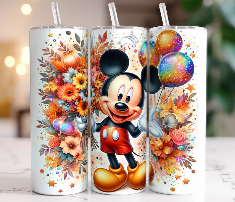 May include: A white tumbler featuring a colourful autumnal floral design and a cartoon Mickey Mouse character. The tumbler comes with a straw and a lid.