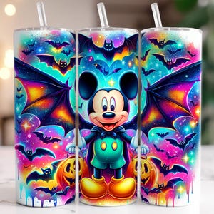 Pu&ograve; includere: Tre bicchieri a tema Halloween con cannucce. Ogni bicchiere presenta un design vibrante di Topolino vestito da pipistrello, circondato da pipistrelli, zucche e uno sfondo galattico colorato. I bicchieri sono cilindrici e sembrano essere di metallo.