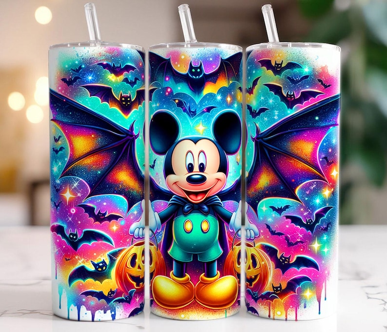Pu&ograve; includere: Tre bicchieri a tema Halloween con cannucce. Ogni bicchiere presenta un design vibrante di Topolino vestito da pipistrello, circondato da pipistrelli, zucche e uno sfondo galattico colorato. I bicchieri sono cilindrici e sembrano essere di metallo.