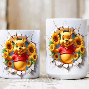 May include: Two white ceramic mugs with a Winnie the Pooh design. The mugs feature a 3D Winnie the Pooh character peeking out of a cracked wall with sunflowers surrounding him. The smaller mug has a handle on the left side, while the larger mug has a handle on the right side.