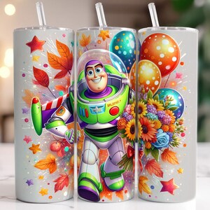 May include: A white tumbler with a colourful design featuring a cartoon image of Buzz Lightyear from the Toy Story franchise. The design also includes autumn leaves, flowers, and balloons.