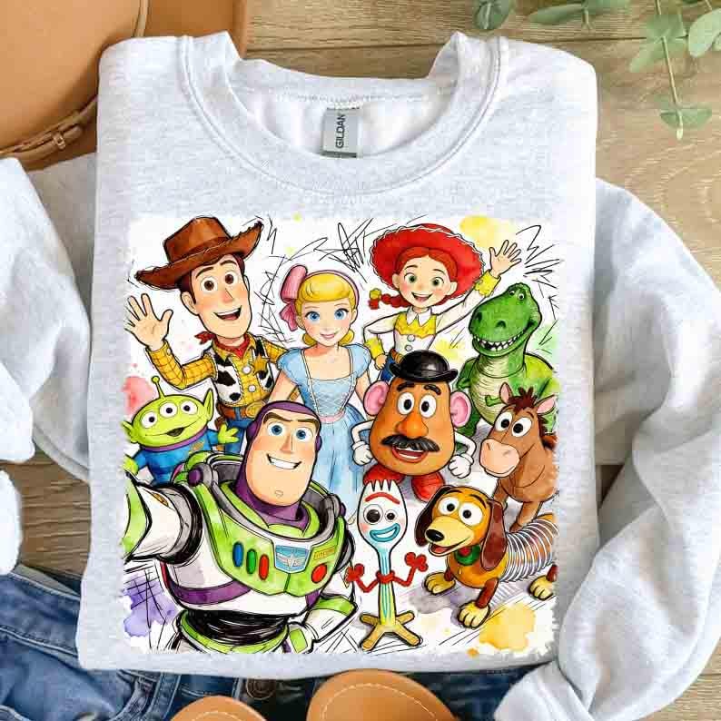 Pode incluir: Camisola cinza claro com um gr&aacute;fico colorido de personagens do Toy Story. O design inclui Woody, Buzz Lightyear, Bo Peep, Jessie, Rex, Sr. Batata e outros. A camisola tem gola redonda.