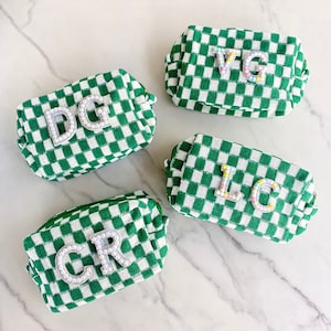 Könnte beinhalten: Vier grüne und weiße karierten Kosmetiktaschen mit verschiedenen Buchstabenkombinationen auf jeder Tasche. Die Buchstaben bestehen aus weißen Perlen mit perlmuttartigem Finish. Die Buchstaben auf den Taschen sind DG, VG, IC und CR.