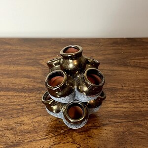 May include: A gold ceramic planter with multiple small pots arranged in a tiered design. The planter has a rustic, textured finish.