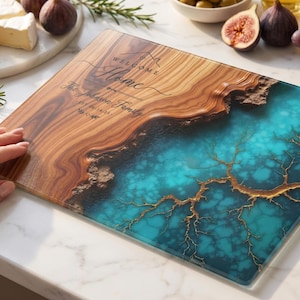 May include: A rectangular wooden cutting board with a turquoise resin design. The board features the text "Welcome Home" and a family name. The board is surrounded by cheese, figs, and grapes.