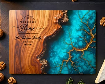 Puede incluir: Tabla de cortar rectangular de madera con un diseño único. El lado izquierdo presenta una veta de madera marrón cálida, mientras que el lado derecho tiene una resina turquesa con vetas doradas en forma de árbol. El texto "WELCOME HOME The Johnson Family" está inscrito en la madera.