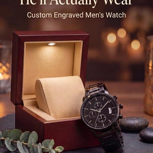 May include: A black metal chronograph watch with a round face and link bracelet, positioned next to an open dark wood presentation box with a beige interior and a small integrated LED light. Text reads: The Anniversary Gift He'll Actually Wear.