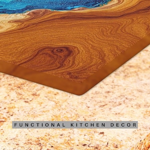 May include: A close-up of a wooden cutting board with a blue epoxy resin inlay. The board has a natural wood grain pattern and is a functional kitchen decor item.