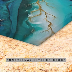 May include: A teal and gold abstract design printed on a glass cutting board. The cutting board is resting on a beige countertop with the text "FUNCTIONAL KITCHEN DECOR" printed on the surface.