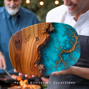 May include: A wooden serving board with a blue and gold resin inlay. The board is oval shaped and has the initials "M B" engraved on the wood.