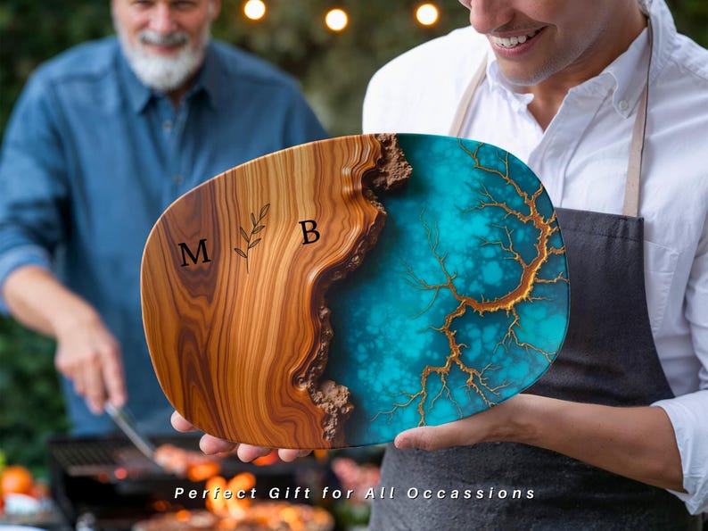 May include: A wooden serving board with a blue and gold resin inlay. The board is oval shaped and has the initials "M B" engraved on the wood.